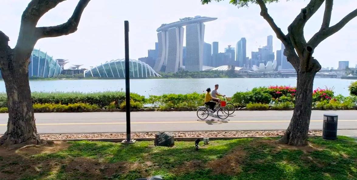 Radweg mit zwei Radfahrern vor der Skyline von Singapur